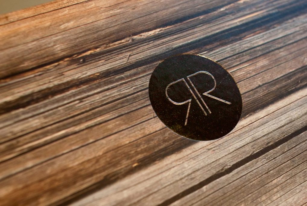 Circular logo featuring "RR" on a wooden texture background.