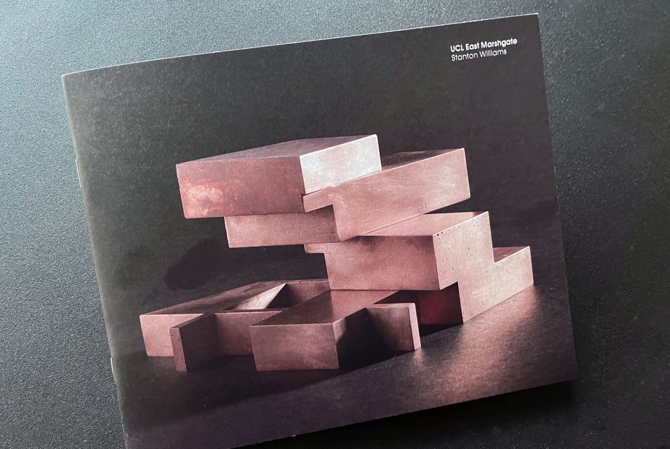 A stack of pink wooden blocks arranged in varying heights on a dark surface.